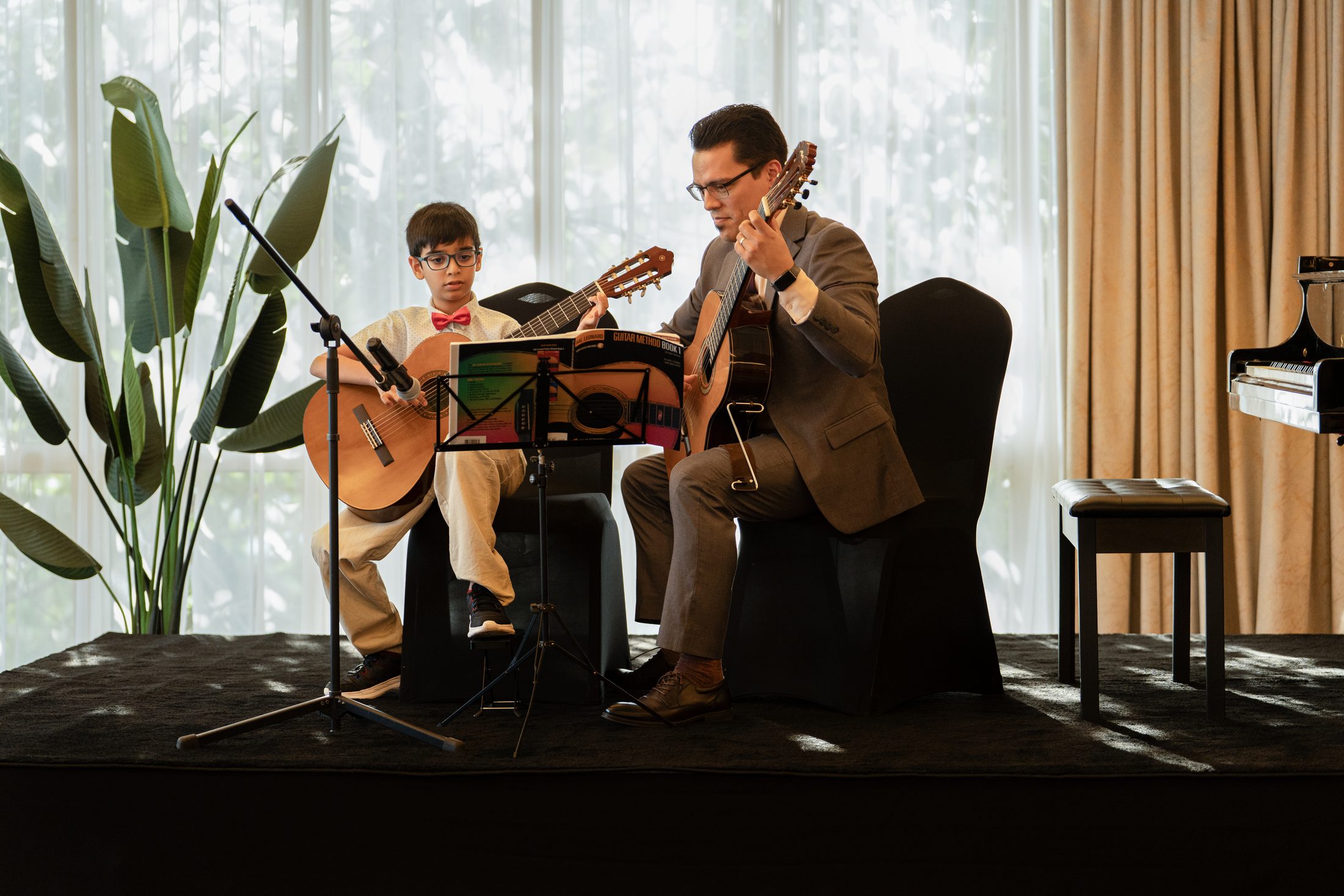A student and teacher playing guitar together at an MJ Strings recital