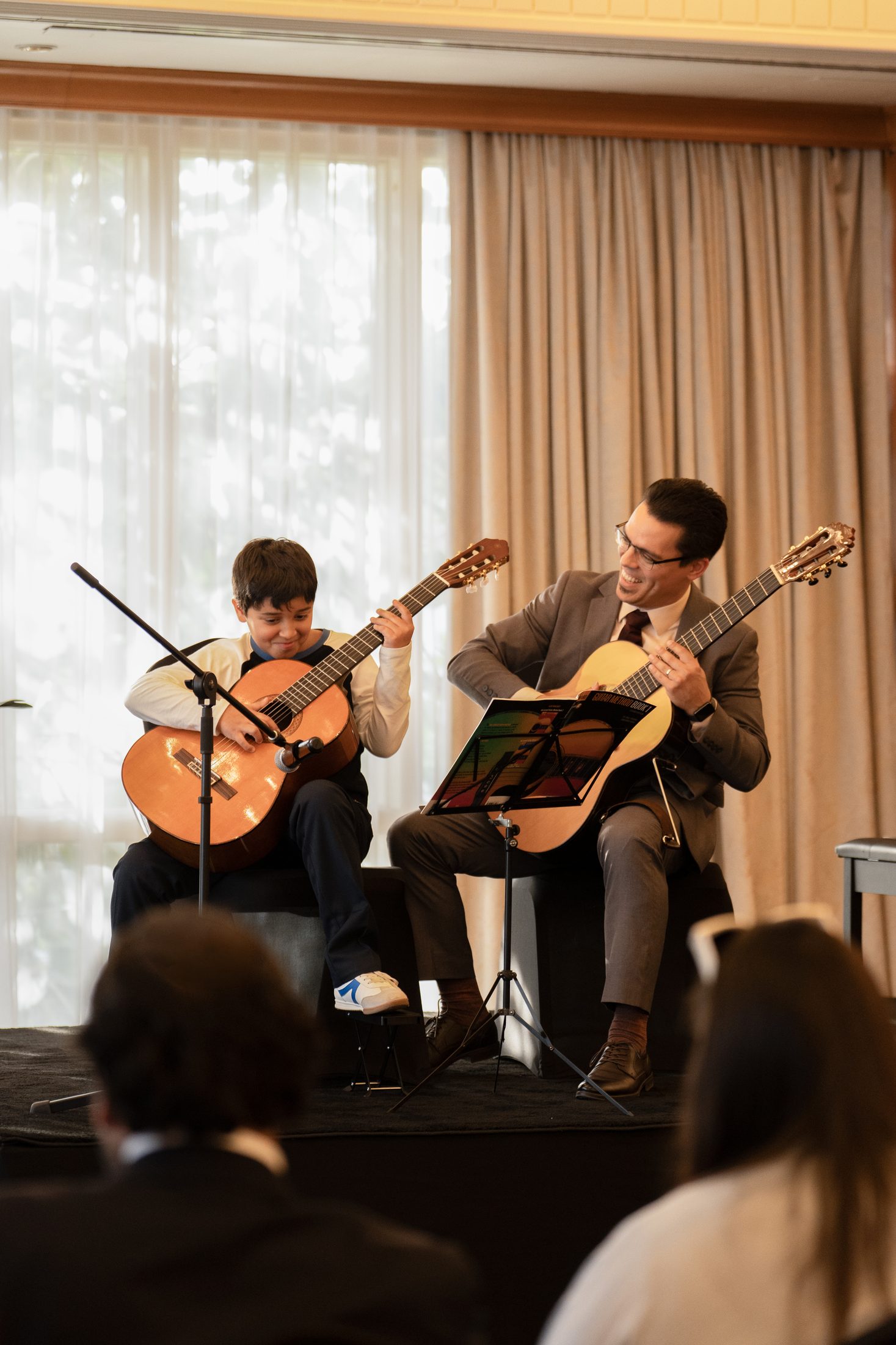 A guitar student performing with a teacher at an MJ Strings recital