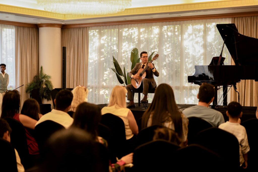 A guitarist performing at an MJ Strings recital in Dubai