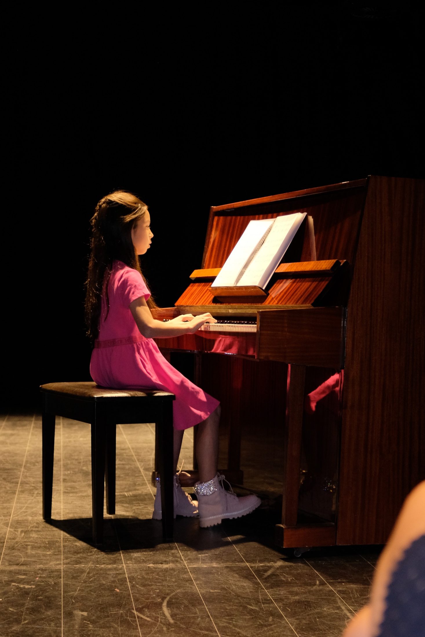 A young piano student performing at an MJ Strings recital